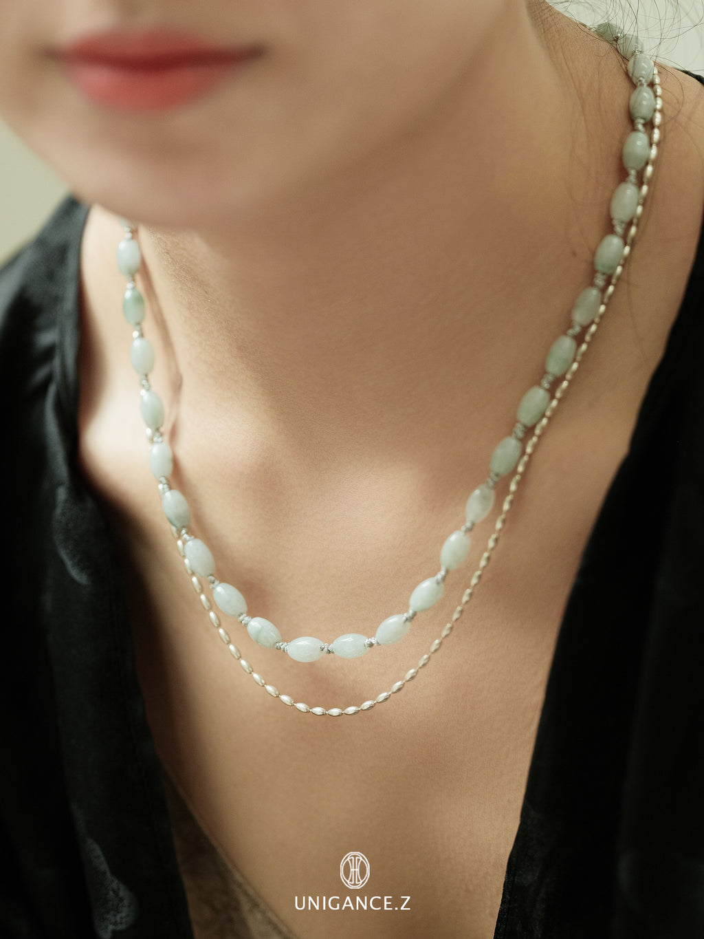 Close-up of a person wearing a layered necklace with a blurred background