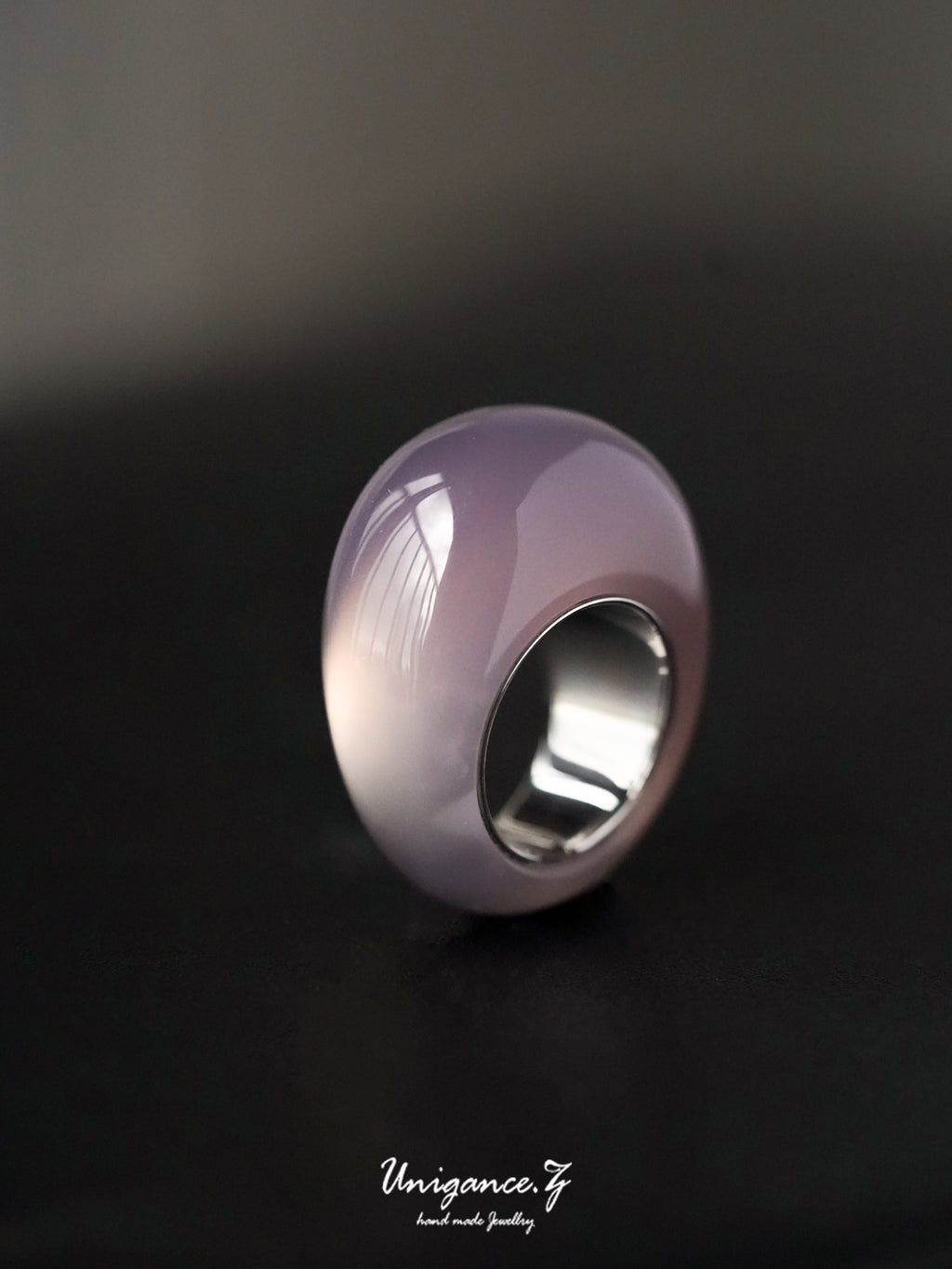 Silver ring with a purple gemstone on a dark background