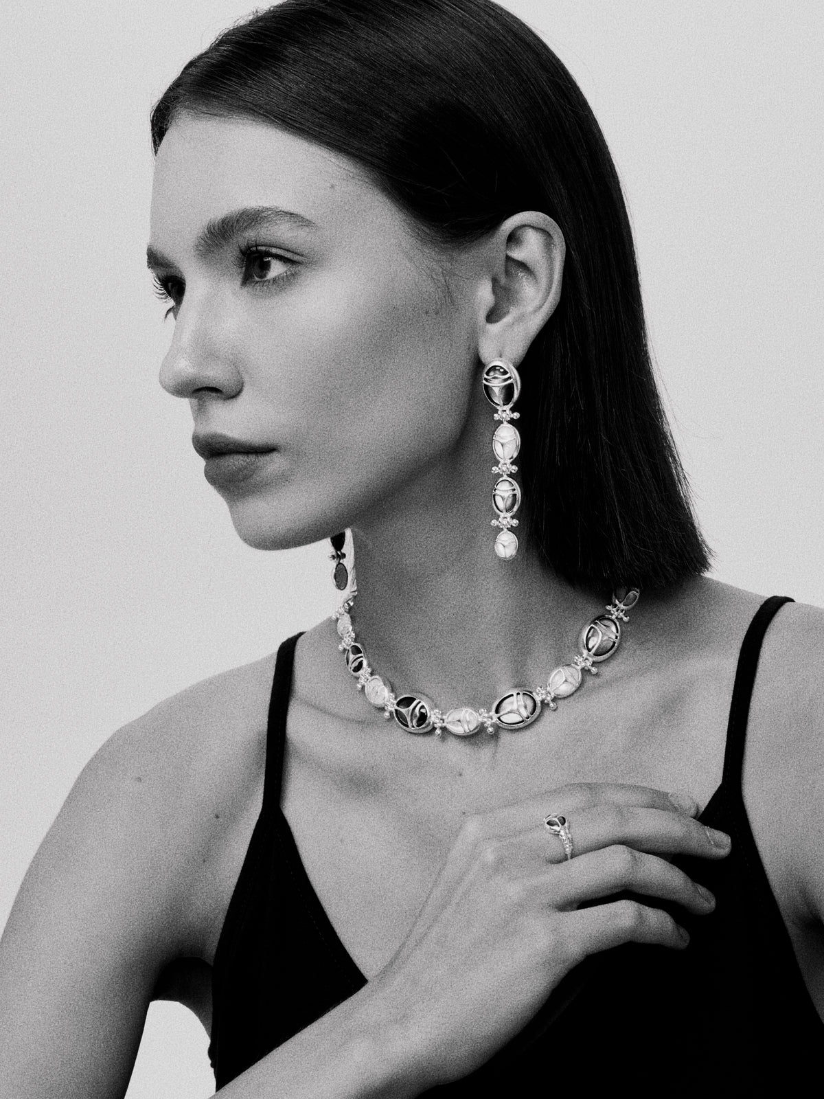 Nomadic Poem · Scarab Mother-of-Pearl Ouroboros Long Earrings — Black and white portrait of a woman wearing elegant jewelry.