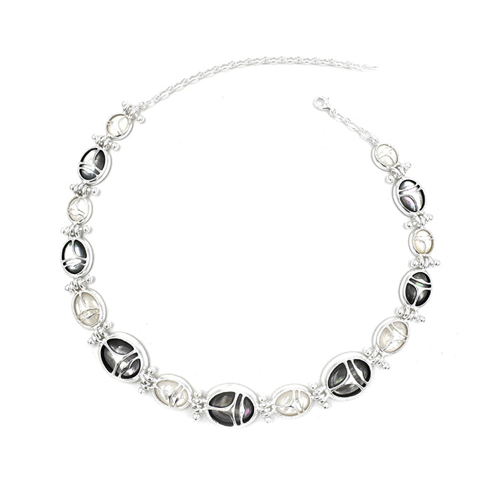 Nomadic Poem · Scarab Mother-of-Pearl Ouroboros Necklace — Necklace with black and white oval-shaped beads on a white