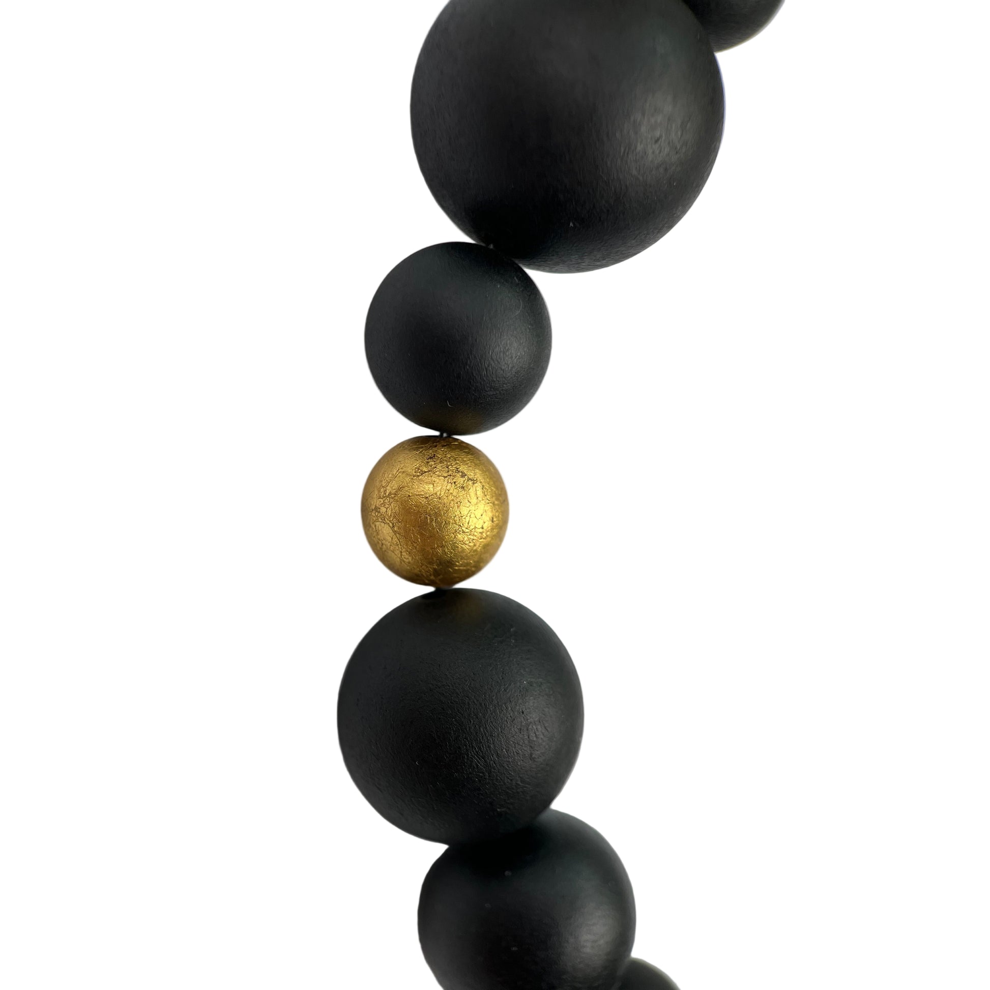 Black beaded necklace with a gold bead on a white background