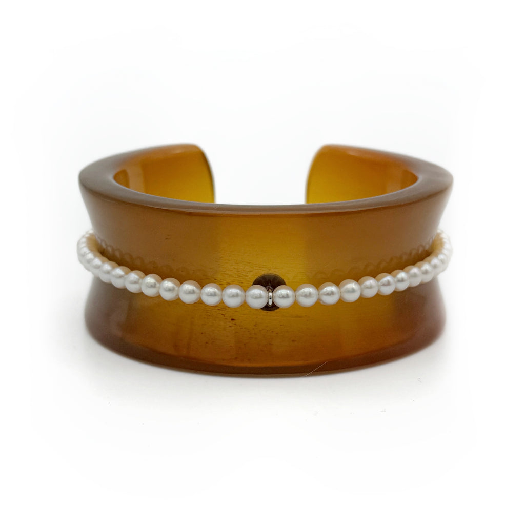 Pearl Inlay Open Cuff Horn Bracelet — Brown cuff bracelet with a white pearl bracelet on top on a white background