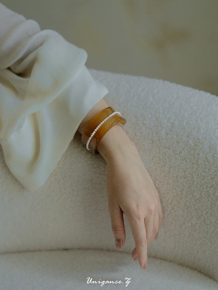 Pearl Inlay Open Cuff Horn Bracelet — Close-up of a hand wearing bracelets on a textured surface with 'Unigance' branding.