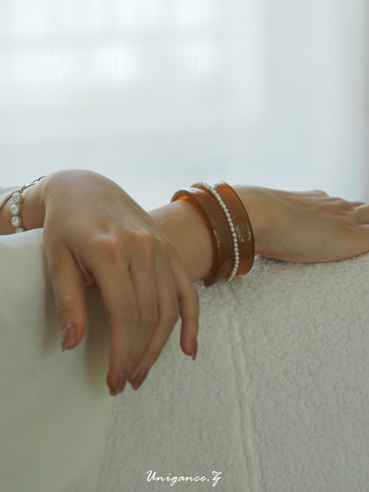 Pearl Inlay Open Cuff Horn Bracelet — Close-up of two hands with bracelets on a light background