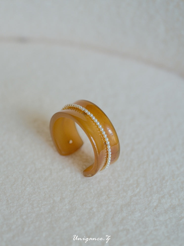 Pearl Inlay Open Cuff Horn Bracelet — Brown bracelet with a textured band on a light background