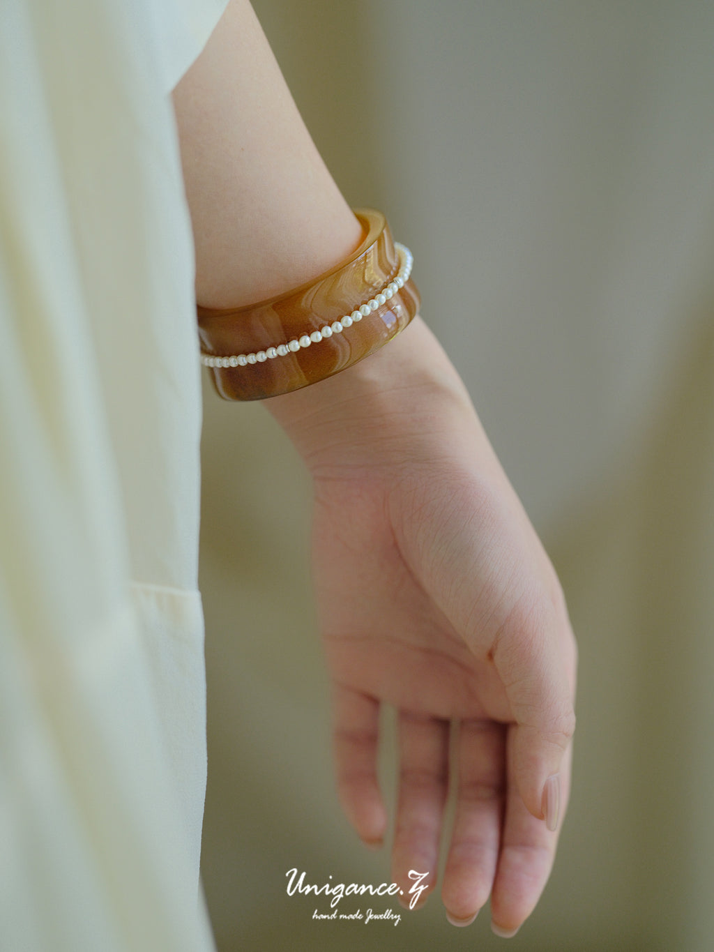 Pearl Inlay Open Cuff Horn Bracelet — Close-up of a hand wearing a brown bracelet with a blurred background