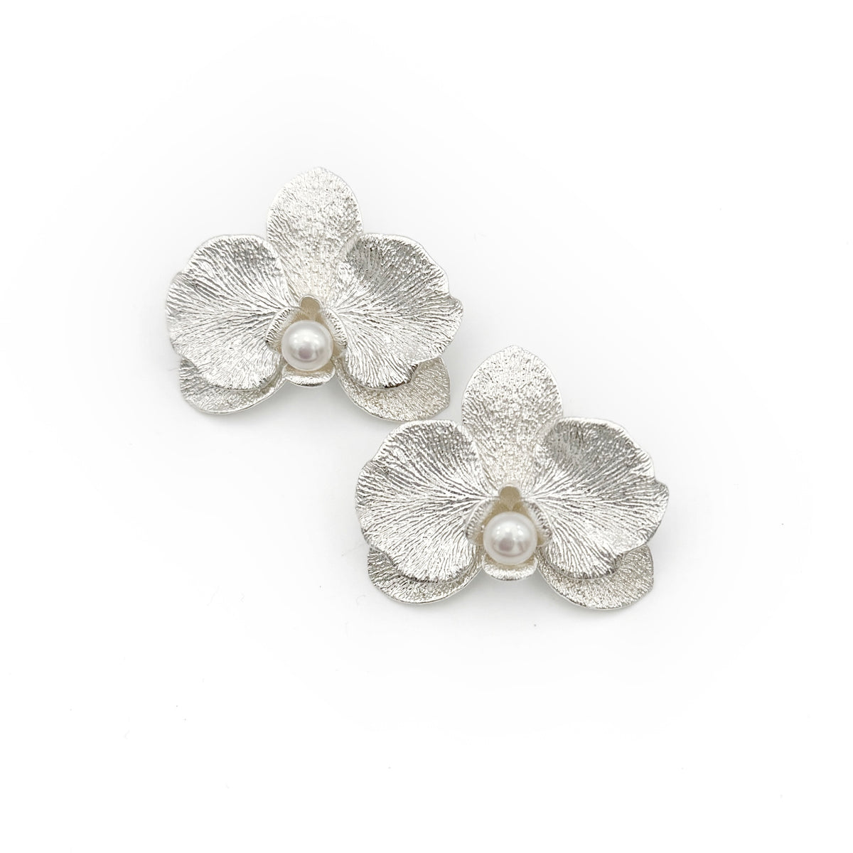 Phalaenopsis Orchid Convertible Earrings — Silver flower-shaped earrings with pearls on a white background