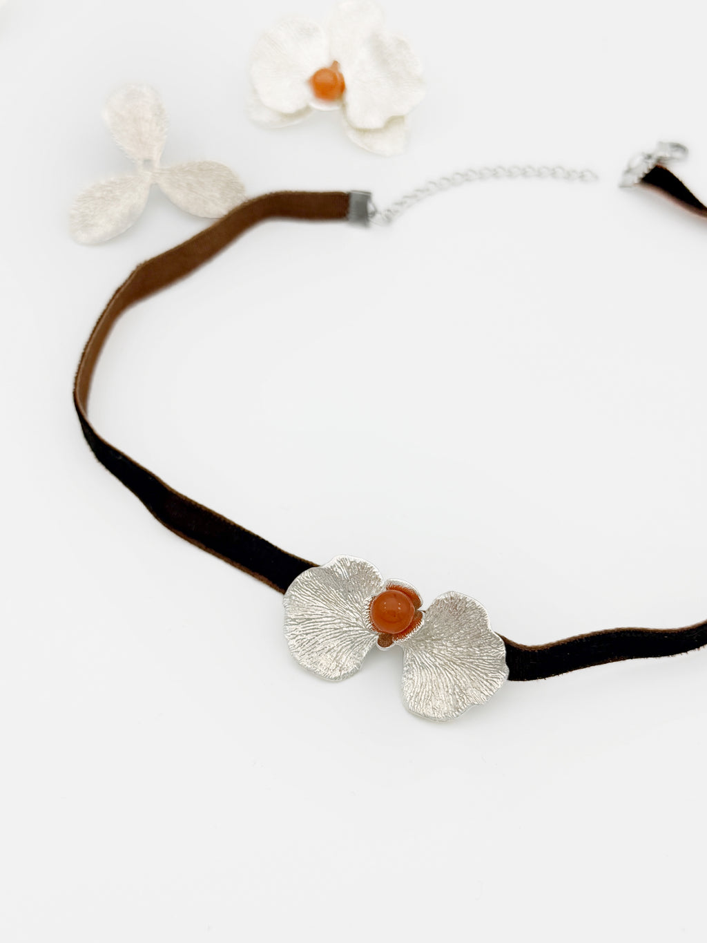 Necklace with silver floral pendants and a brown bead on a white background