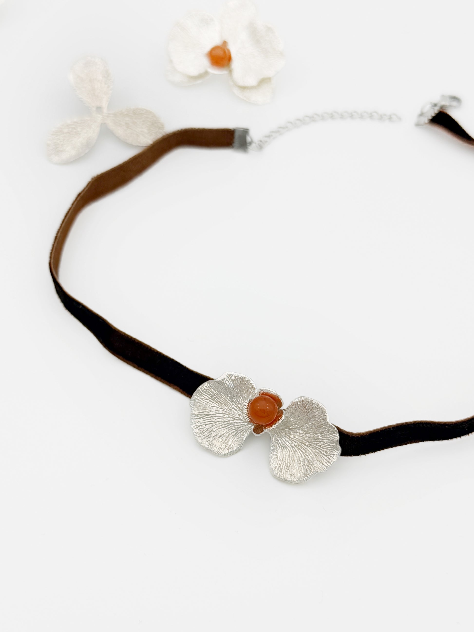 Necklace with silver floral pendants and a brown bead on a white background