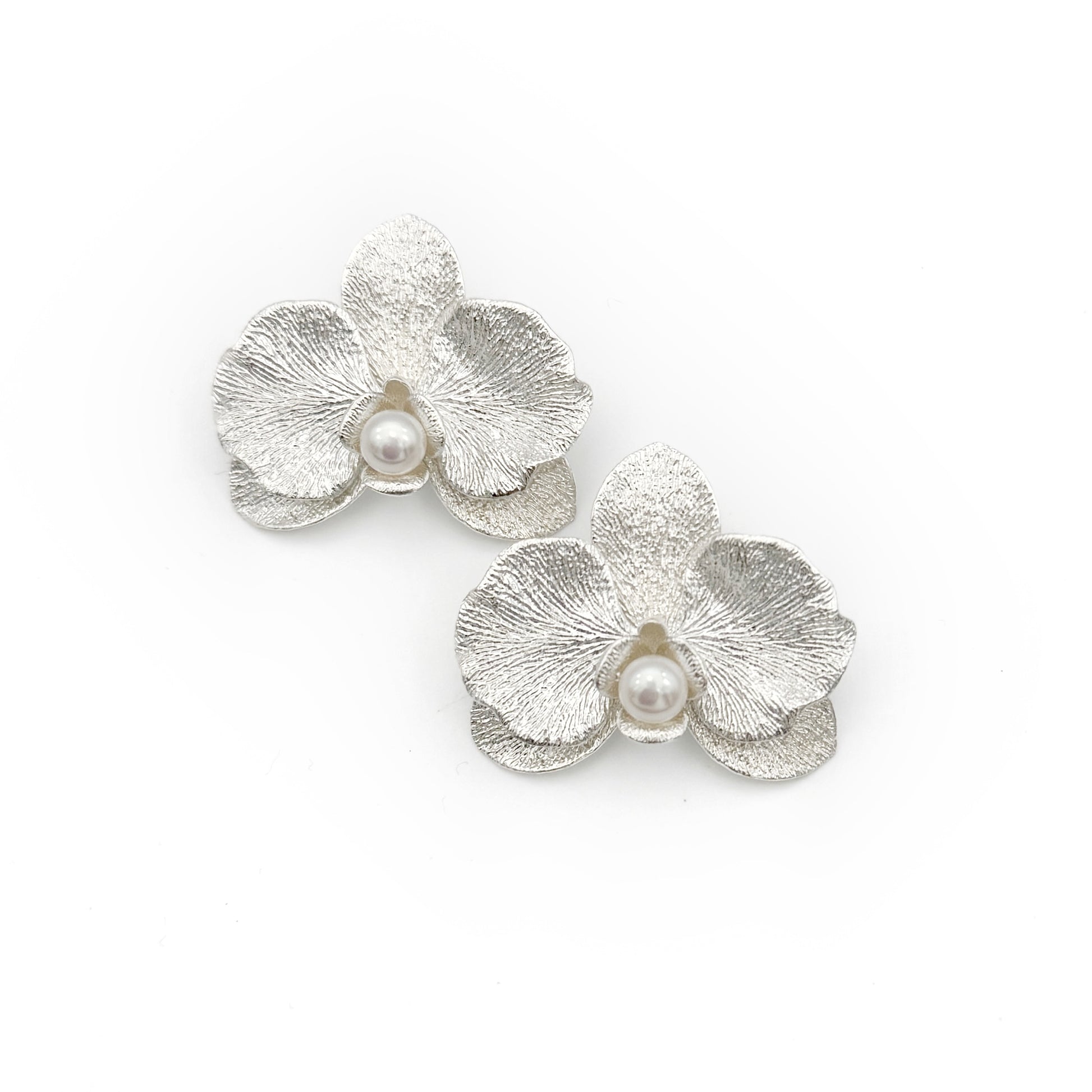 Silver flower-shaped earrings with pearls on a white background