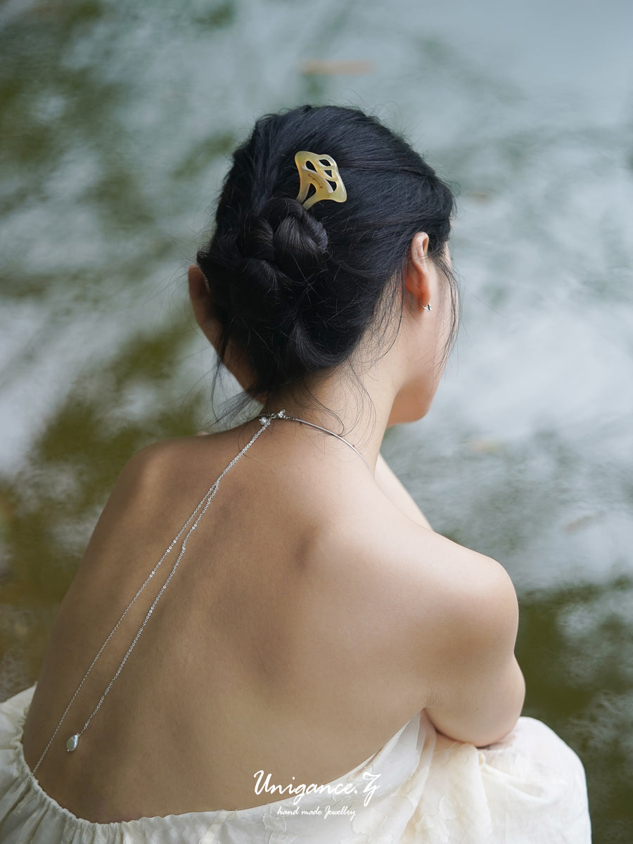 Woman with a decorative hair clip looking away from the camera with a blurred natural background