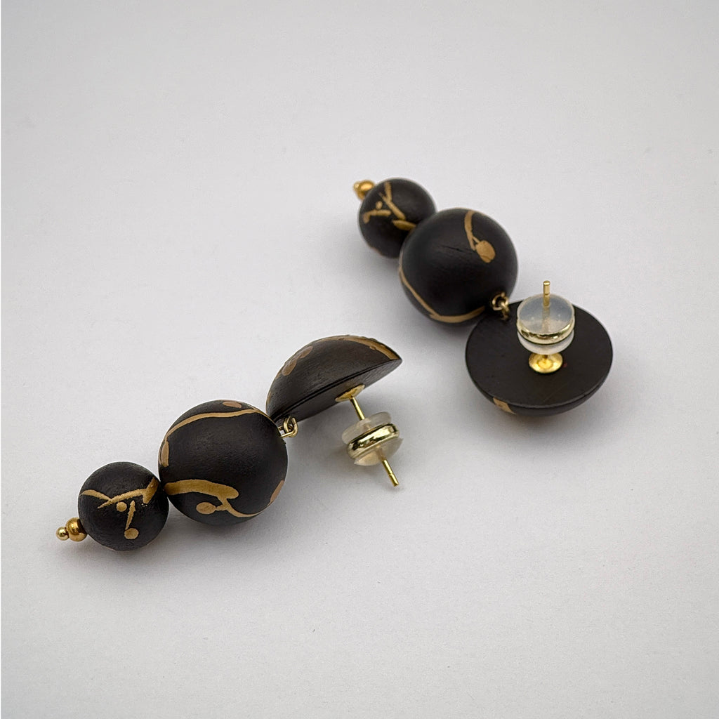 Plum Blossom Lacquer Quasi-Maki-e Earrings — Black and gold beaded earrings on a light gray background
