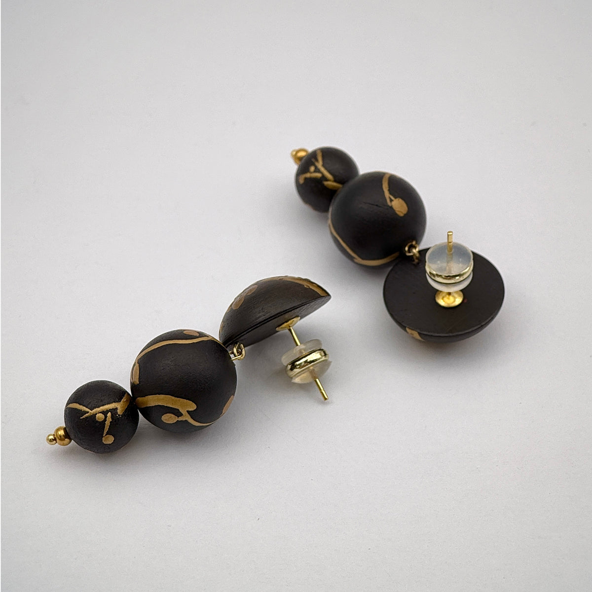 Plum Blossom Lacquer Quasi-Maki-e Earrings — Black and gold beaded earrings on a light gray background