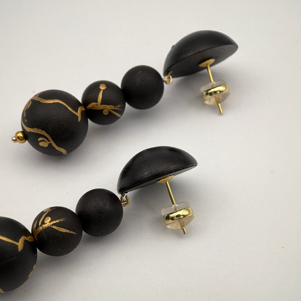 Plum Blossom Lacquer Quasi-Maki-e Long Earrings — Black beaded earrings with gold accents on a white background
