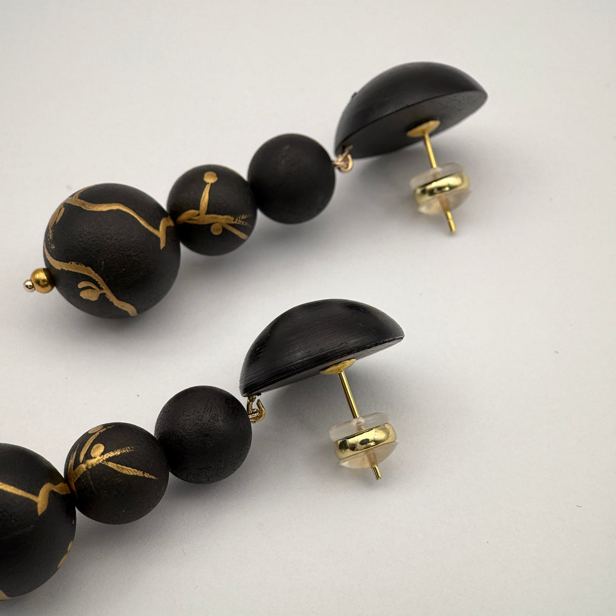Plum Blossom Lacquer Quasi-Maki-e Long Earrings — Black beaded earrings with gold accents on a white background
