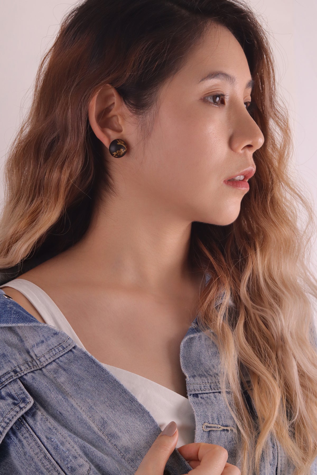 Plum Blossom Lacquer Quasi-Maki-e Stud Earrings — Woman wearing a denim jacket with a neutral background