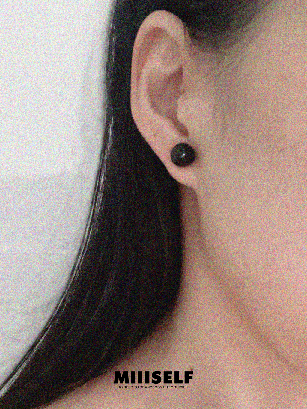 Rain Drop Onyx Convertible Earrings — Close-up of an ear wearing a black stud earring with 'MIIISELF' branding.