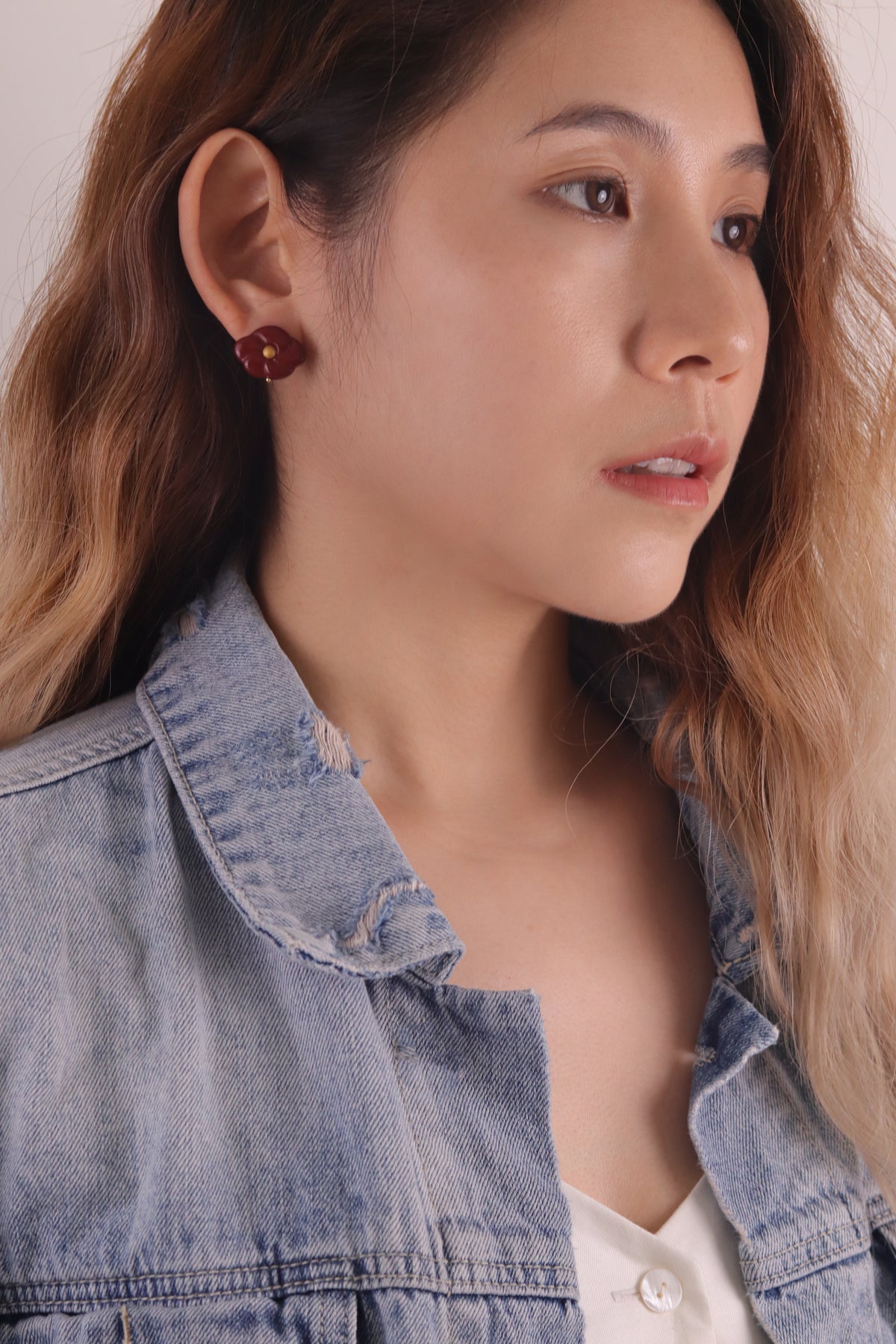 Red Peach Blossom Lacquer Quasi-Maki-e Earrings — Close-up of a person wearing a denim jacket with a neutral background