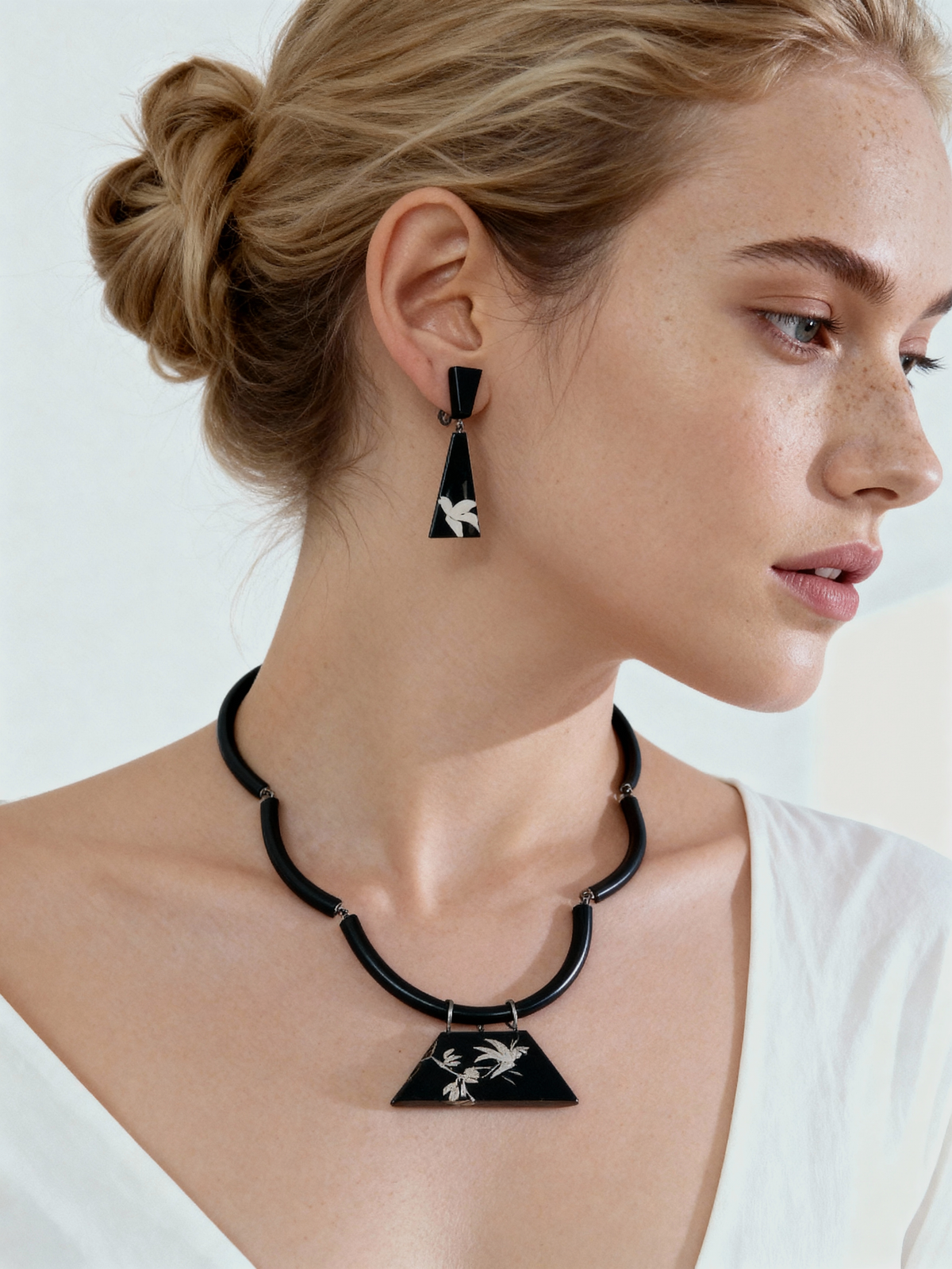 Rising Joy Lacquer Quasi-Maki-e Earrings — Woman wearing a black and white geometric necklace and earrings on a plain