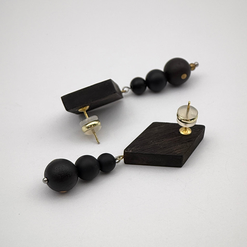 Rising Mountain Lacquer Quasi-Maki-e Earrings — Black beaded and geometric wooden earrings on a white background