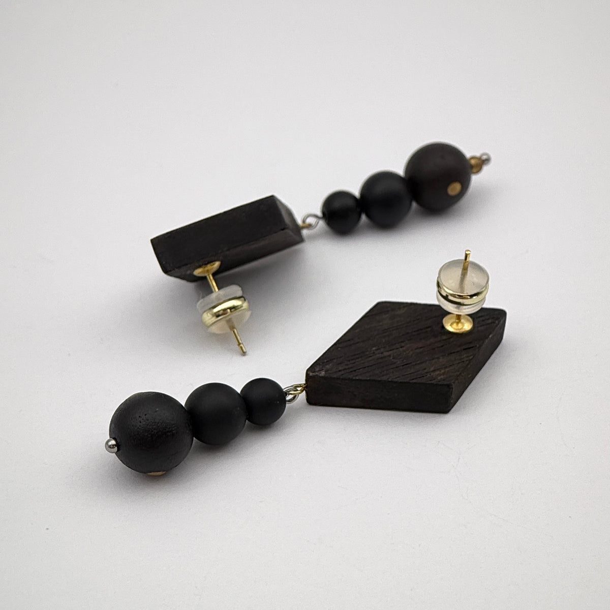 Rising Mountain Lacquer Quasi-Maki-e Earrings — Black beaded and geometric wooden earrings on a white background