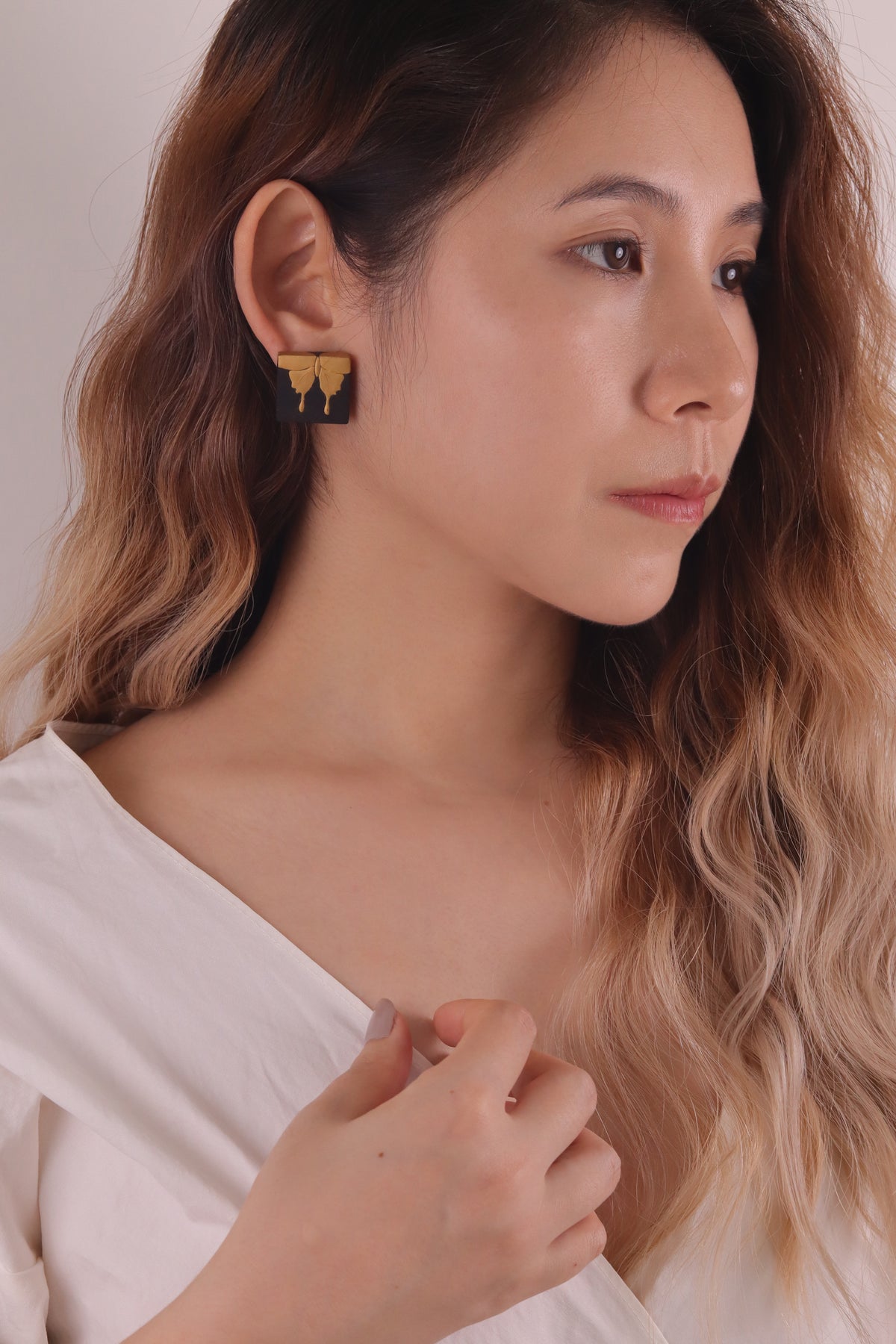 Secret Flower Lacquer Quasi-Maki-e Earrings — Woman wearing gold earrings with a neutral background