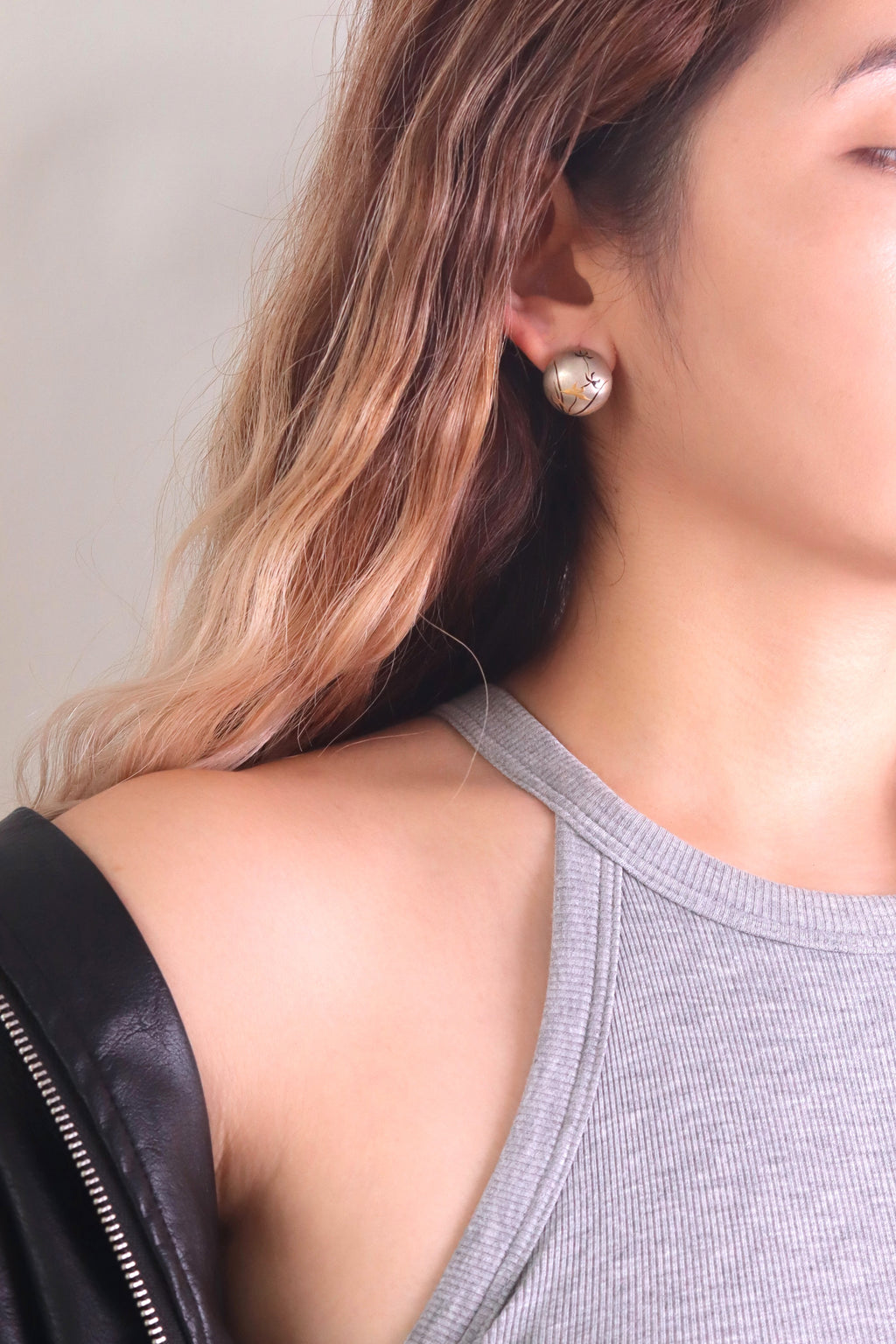 Silver Orchid Lacquer Quasi-Maki-e Stud Earrings — Close-up of a person wearing a gray tank top and black leather jacket with
