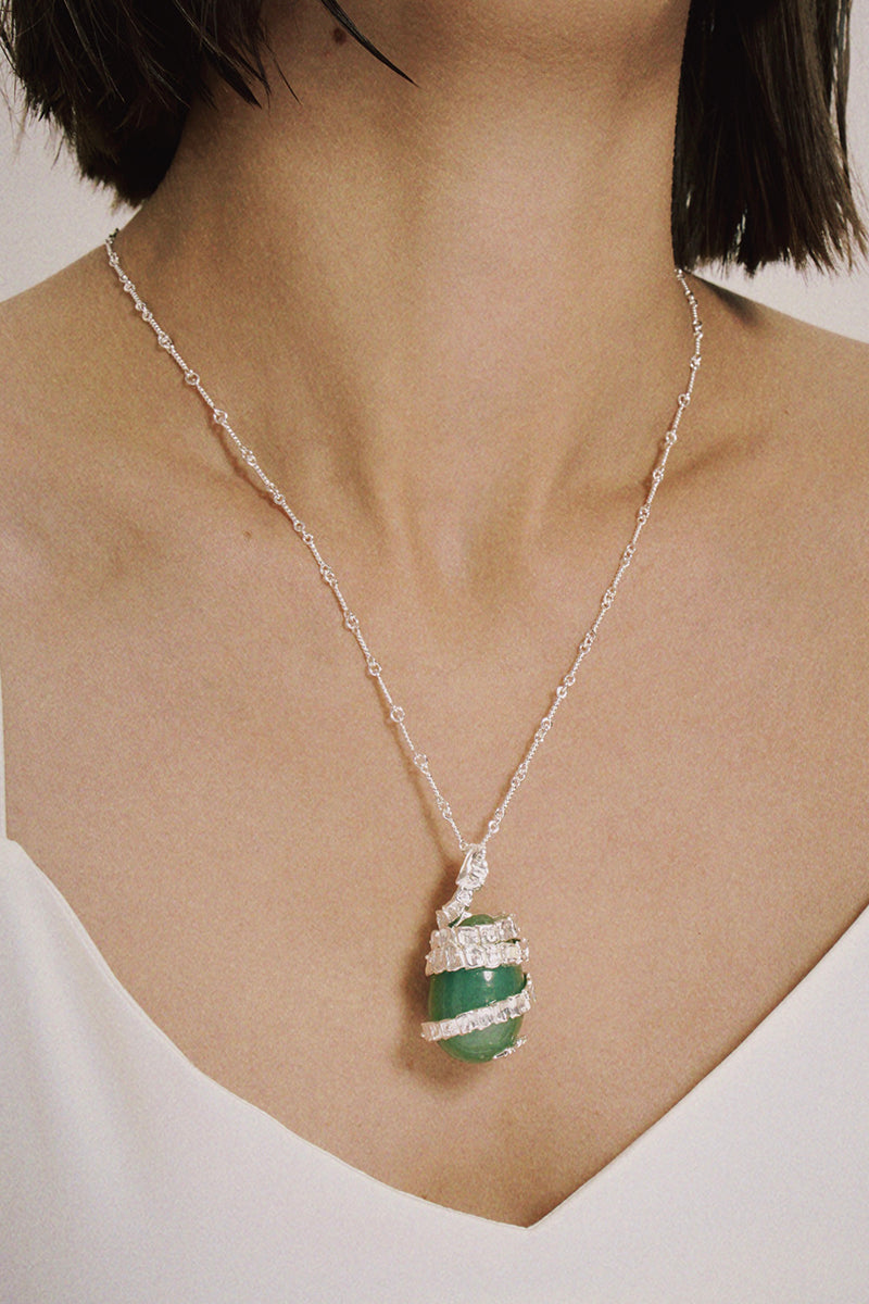 Silver Serpent Guardian Necklace — Necklace with a green pendant worn by a person