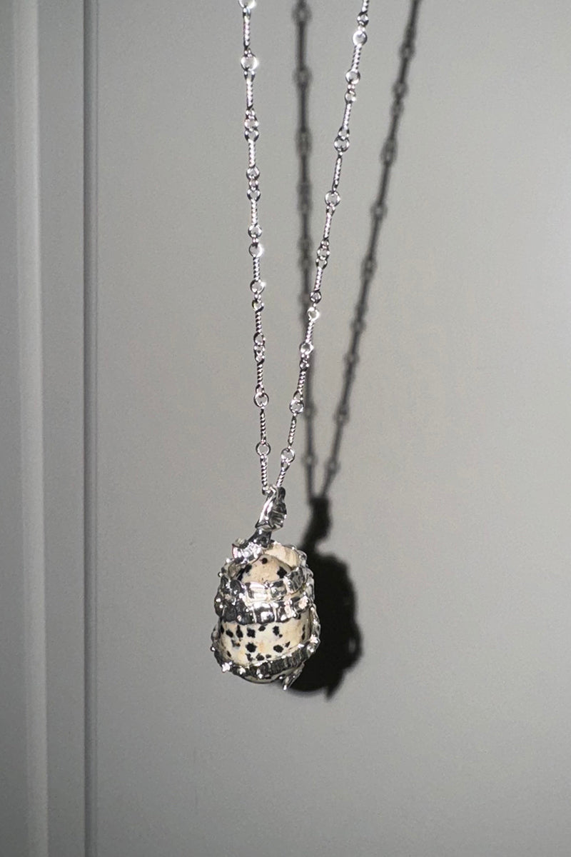 Silver Serpent Guardian Necklace — Silver necklace with a textured pendant on a gray background