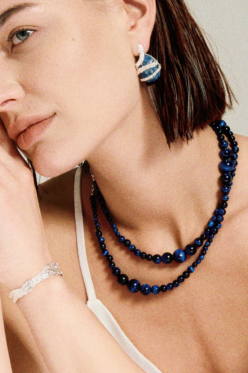 Silver Serpent Guardian Stud Earrings — Woman wearing a blue beaded necklace and earrings with a neutral background