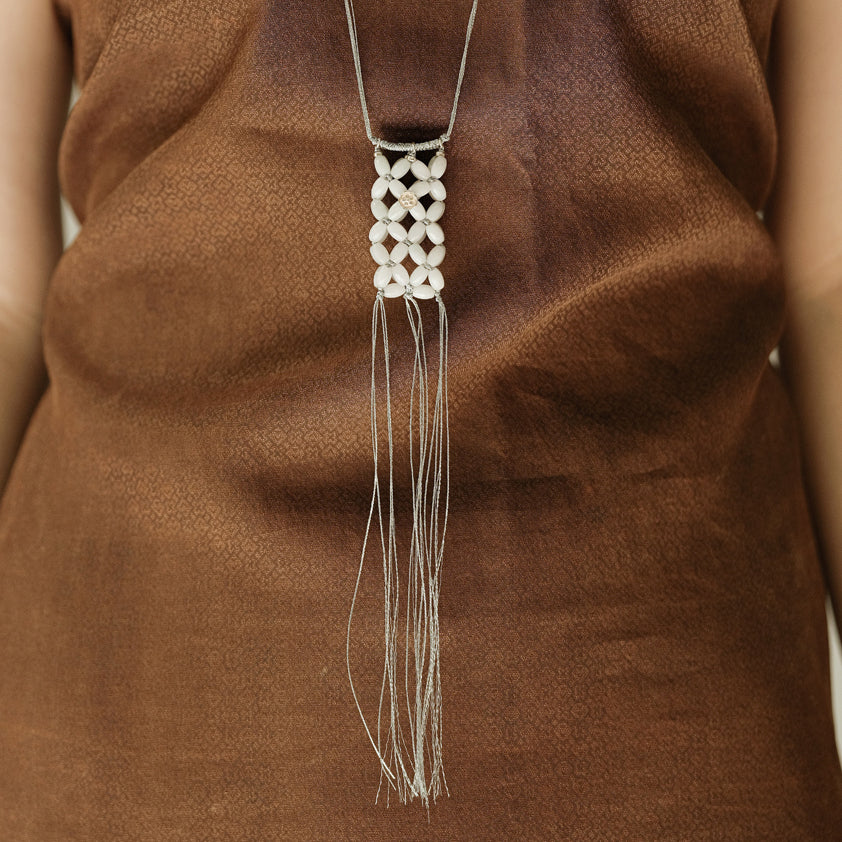 Small Jade Beaded Pouch — Necklace with a geometric pendant and tassels on a brown fabric background