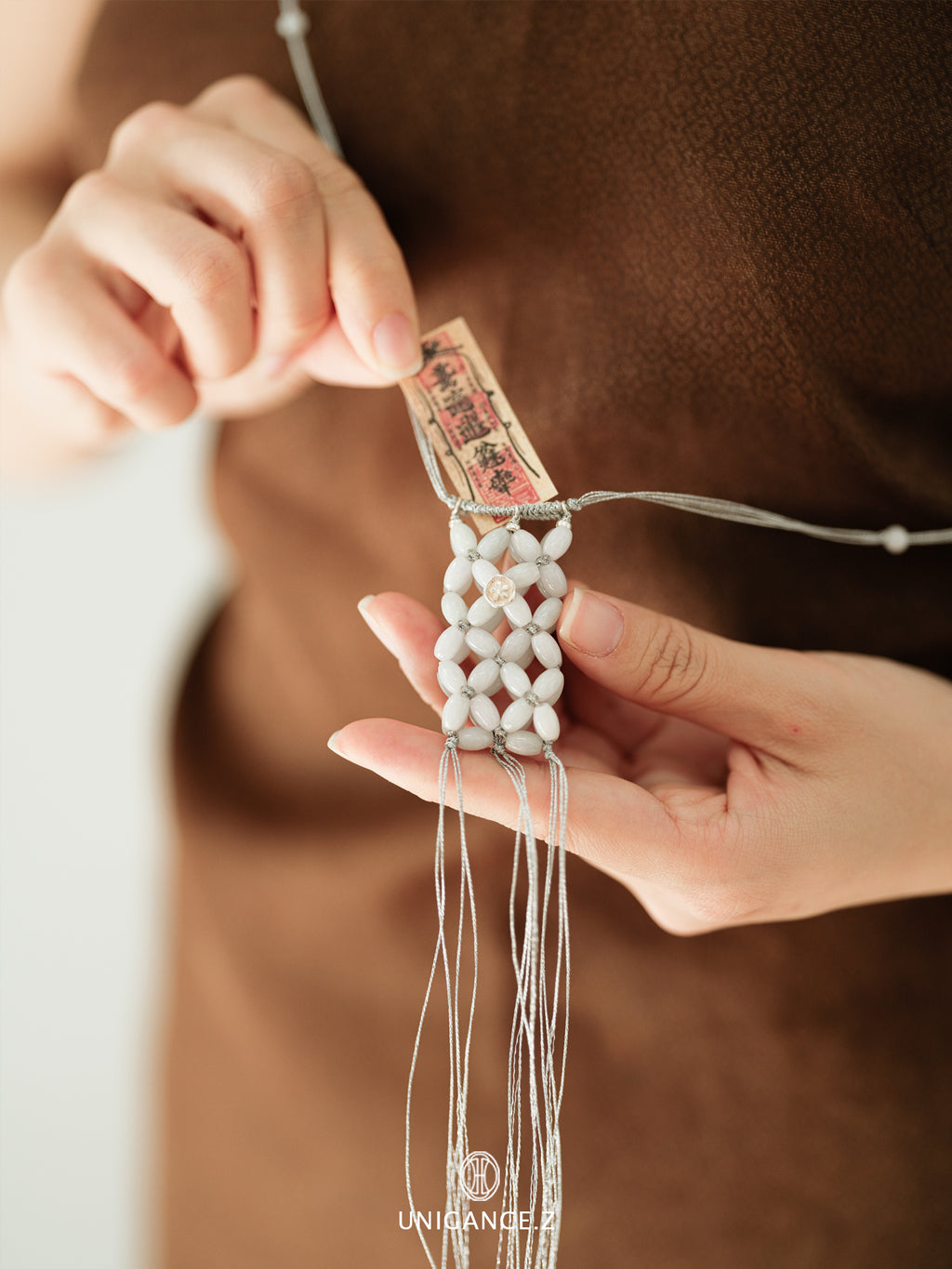 Small Jade Beaded Pouch — Close-up of hands holding a beaded necklace with a blurred background