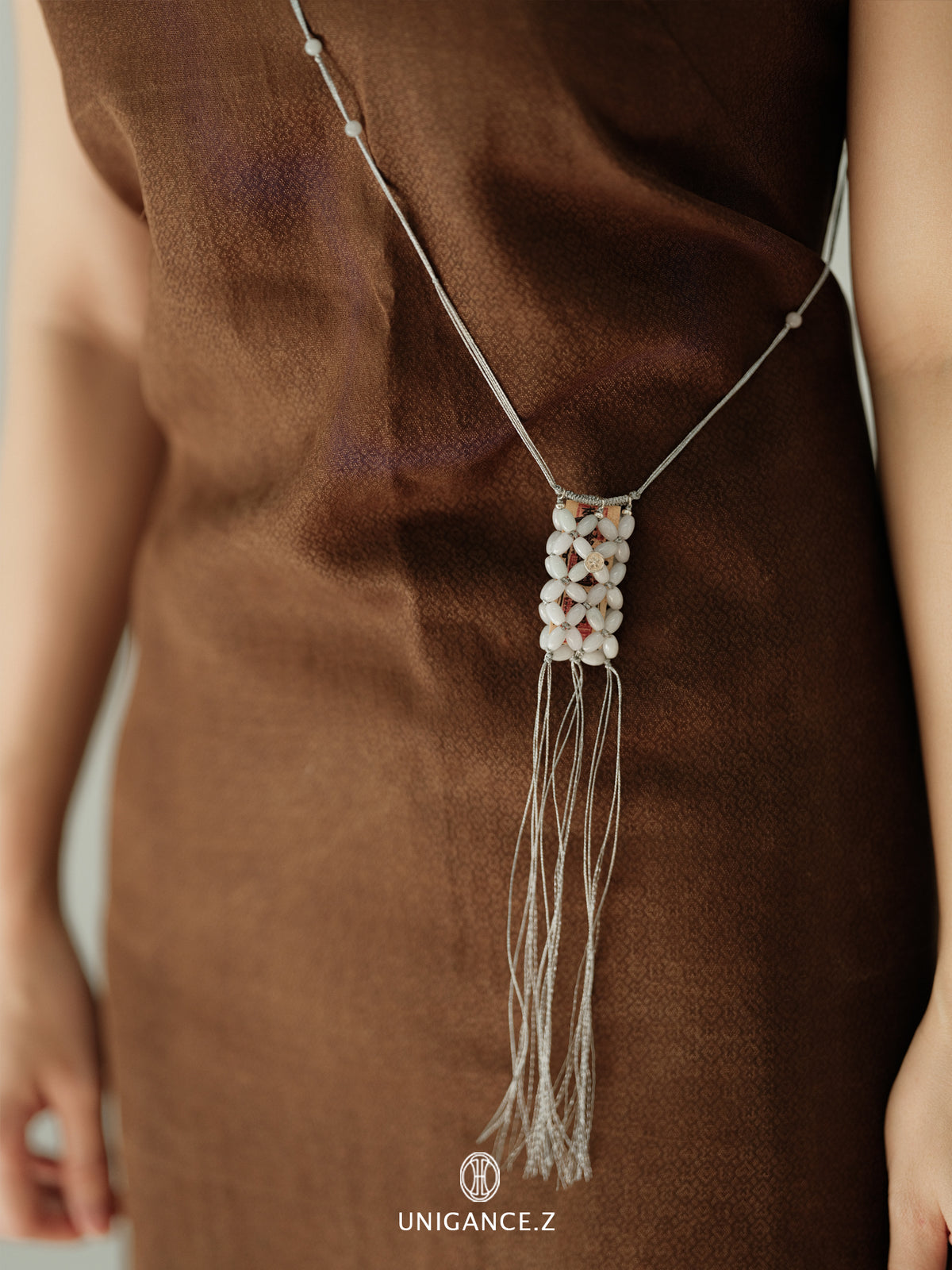 Small Jade Beaded Pouch — Necklace with tassels on a brown fabric background, featuring the brand 'UNIGANCE.Z'.