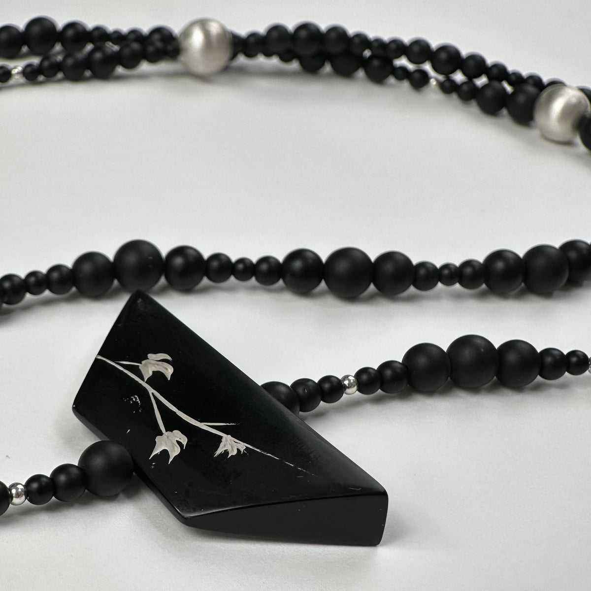 Snow Sparrow Lacquer Quasi-Maki-e Long Lariat Necklace — Black beaded necklace with a triangular pendant on a white