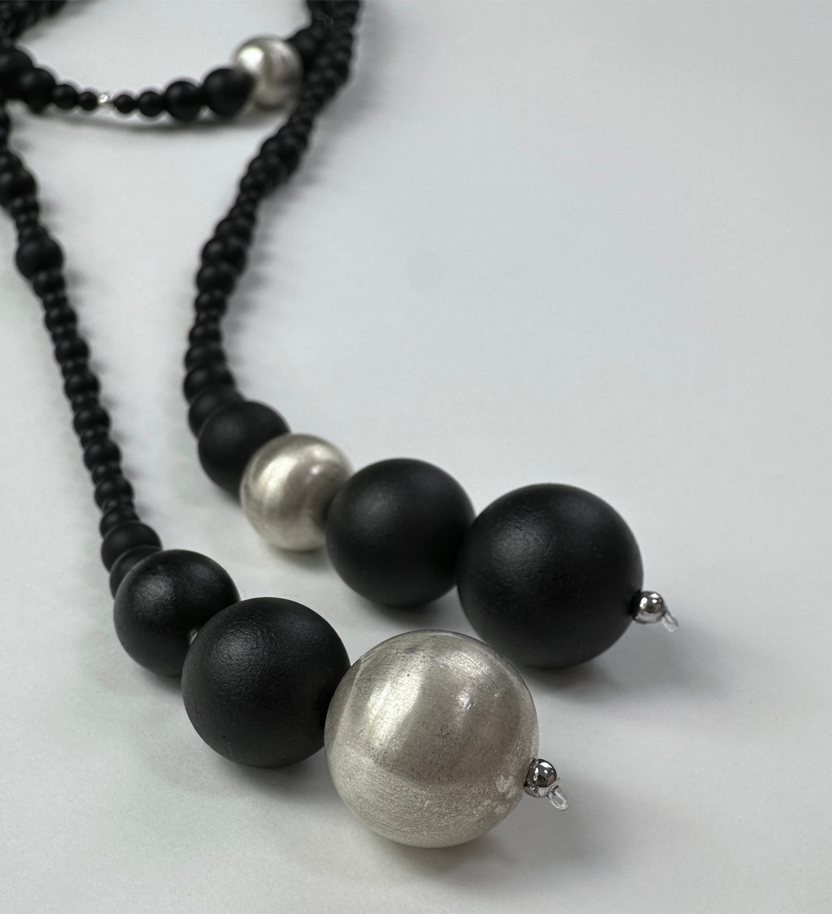 Snow Sparrow Lacquer Quasi-Maki-e Long Lariat Necklace — Necklace with black and silver beads on a light gray background
