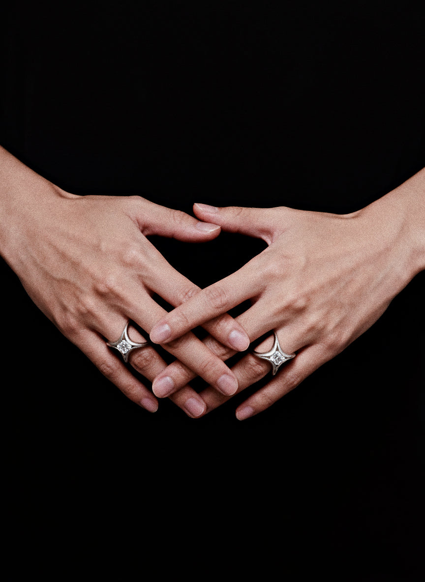 Stellar Keystone I · Moissanite & Silver Ring — Two hands with diamond rings forming a heart shape on a black background