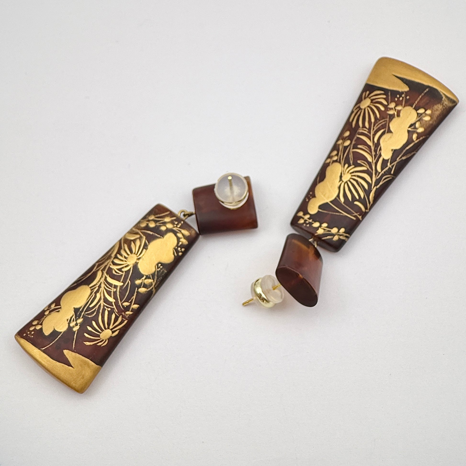 Sunset Watergrass Lacquer Quasi-Maki-e Earrings — Pair of earrings in brown cases with gold floral patterns on a white