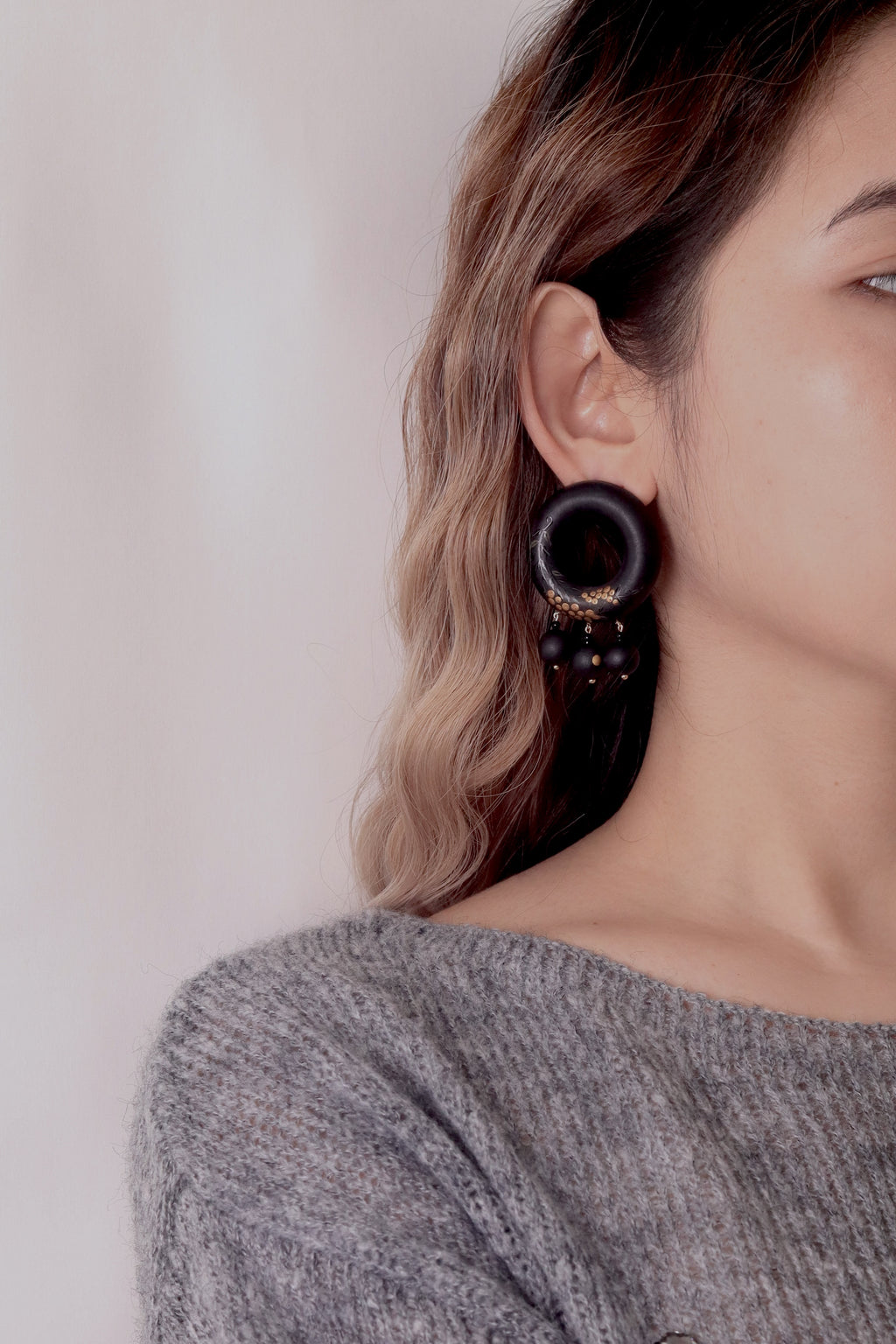 Tenjiku Black Lacquer Drop Earrings — Close-up of a person wearing a black hoop earring against a neutral background