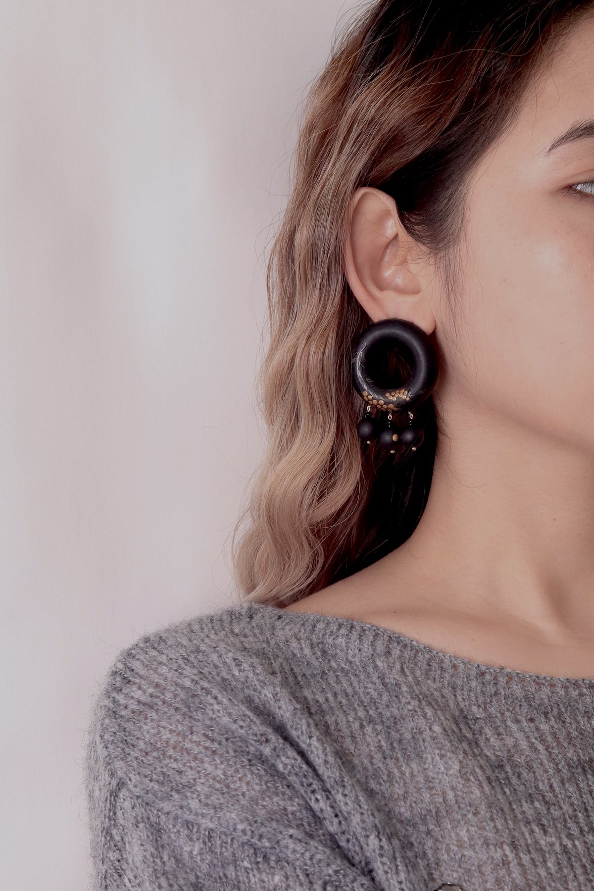 Tenjiku Black Lacquer Drop Earrings — Close-up of a person wearing a black hoop earring against a neutral background