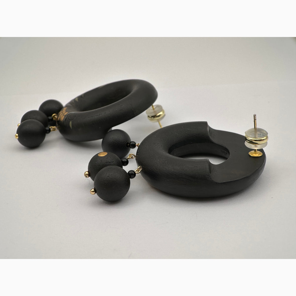 Tenjiku Black Lacquer Drop Earrings — Black hoop earrings with spherical beads on a light gray background