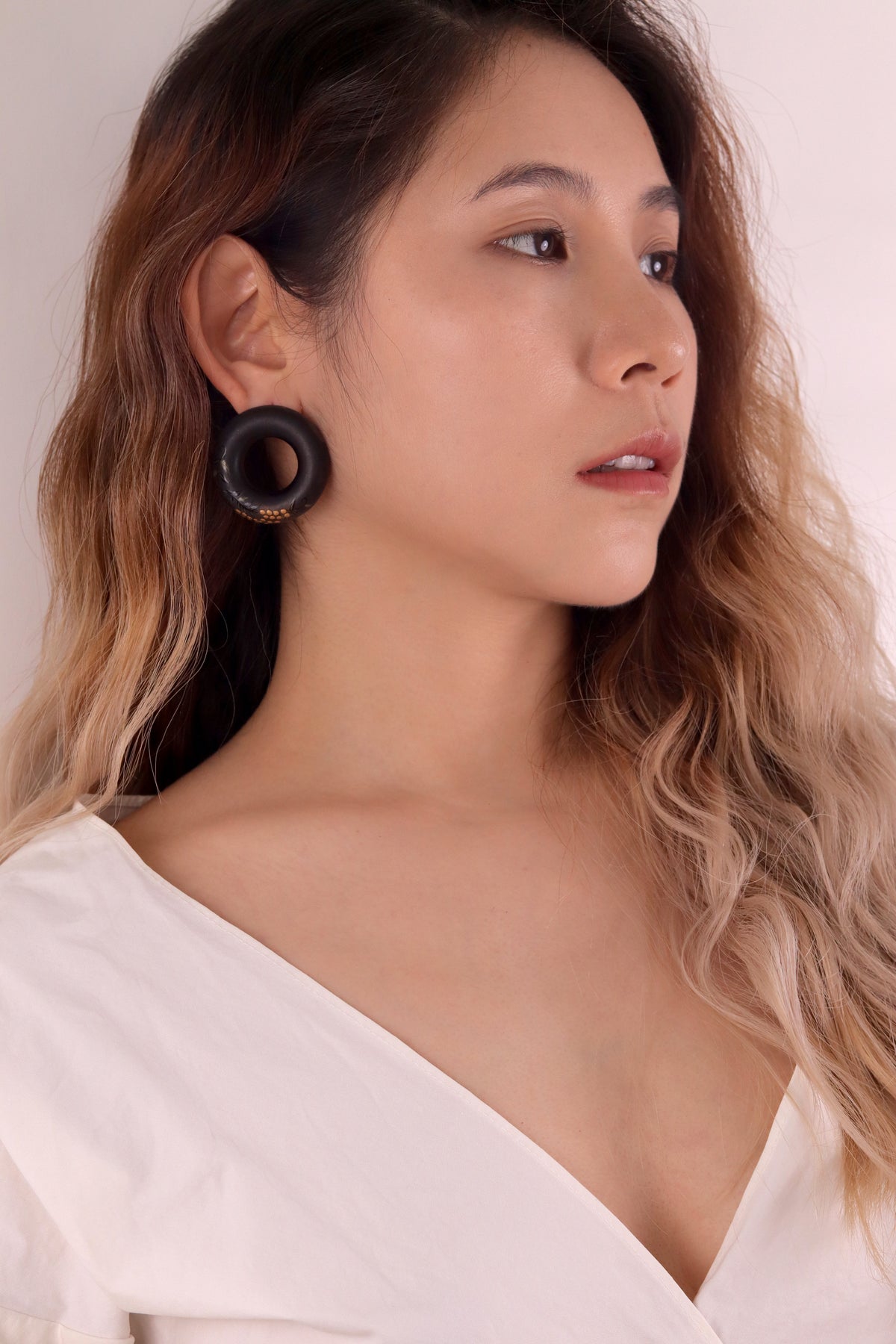 Tenjiku Black Lacquer Quasi-Maki-e Earrings — Woman wearing large hoop earrings with a plain background