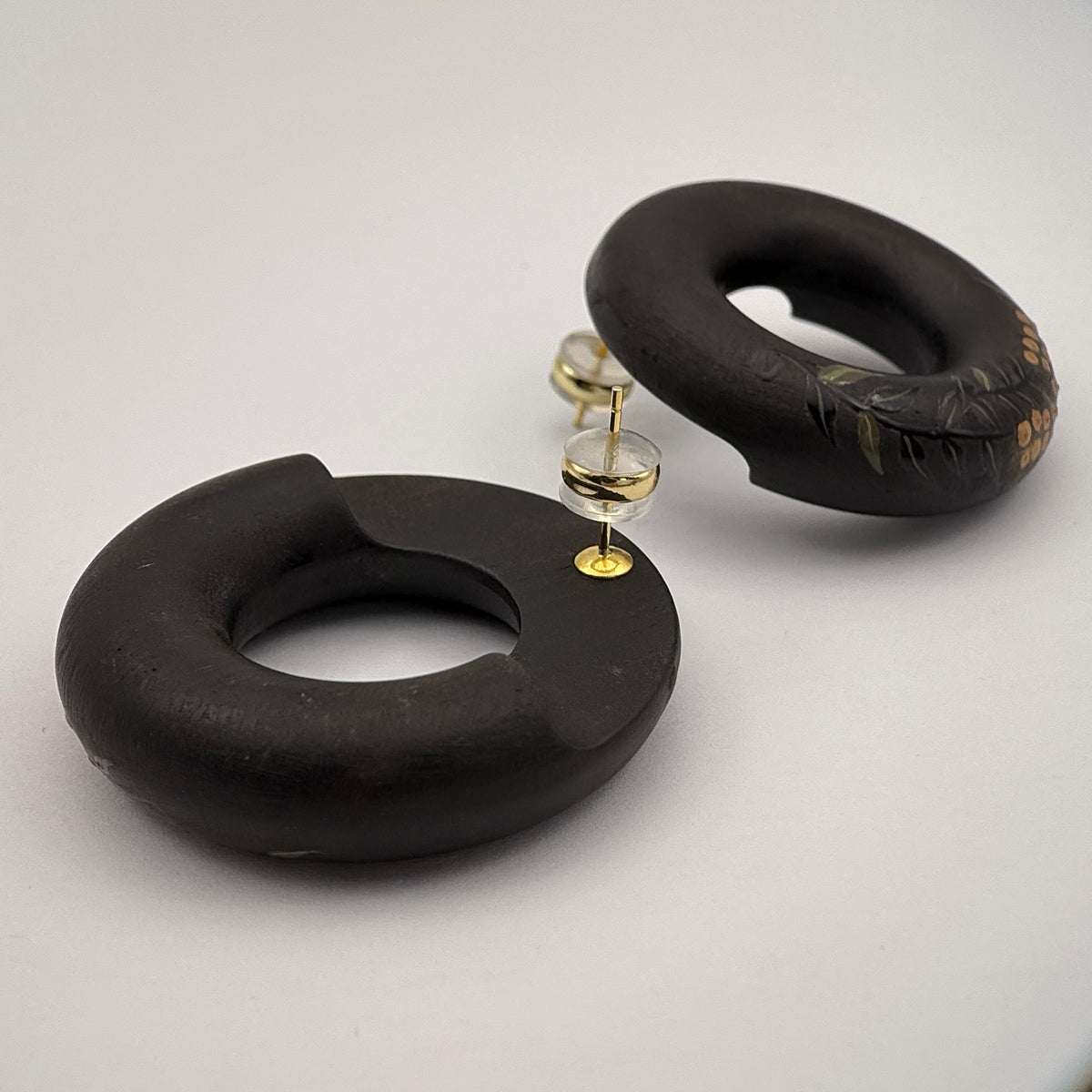 Tenjiku Black Lacquer Quasi-Maki-e Earrings — Black hoop earrings on a light gray background