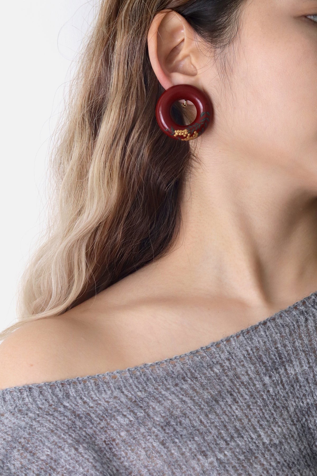 Tenjiku Red Lacquer Quasi-Maki-e Earrings — Close-up of a person wearing a burgundy hoop earring with gold accents.