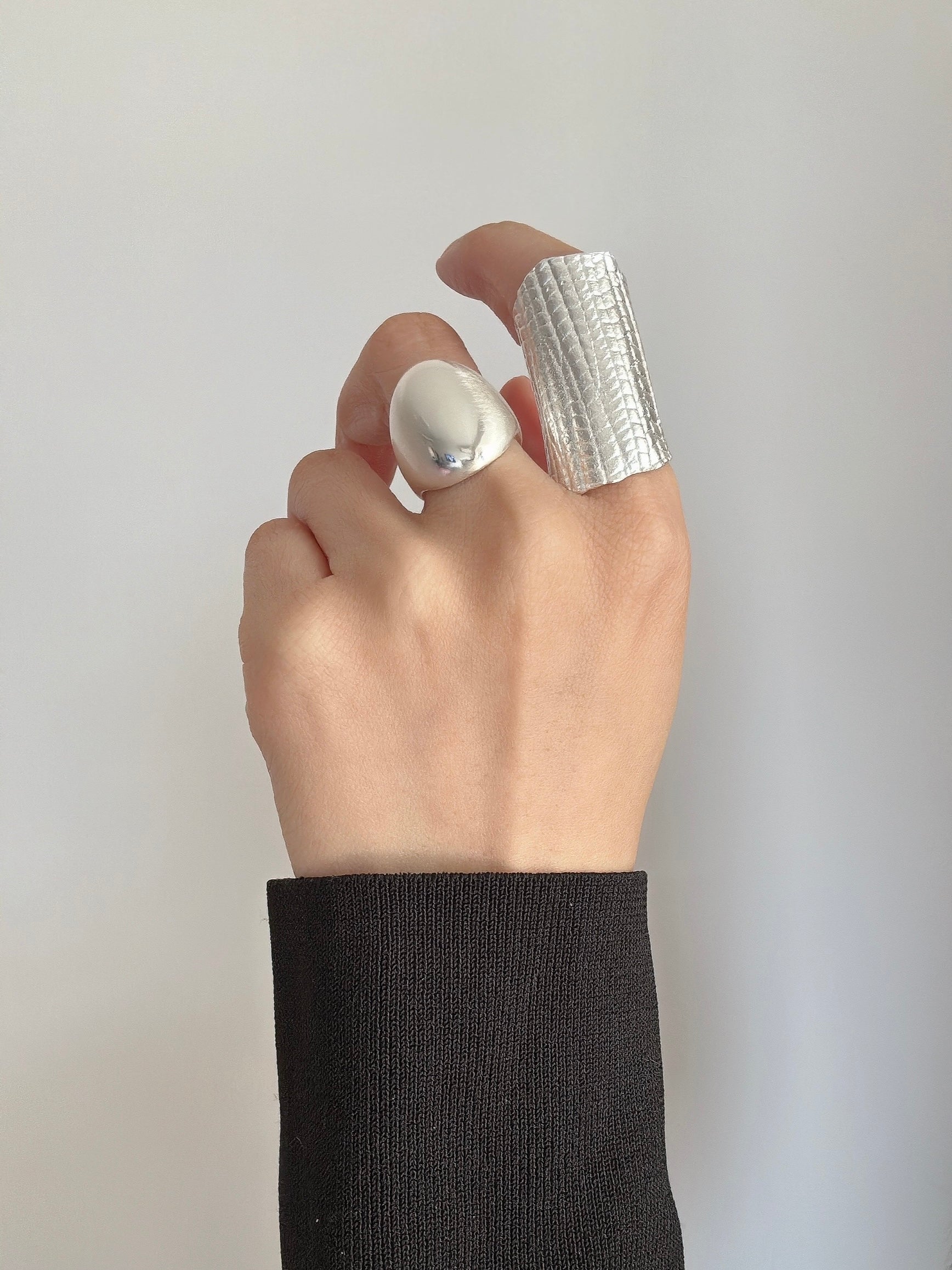Hand wearing a silver ring on a plain background