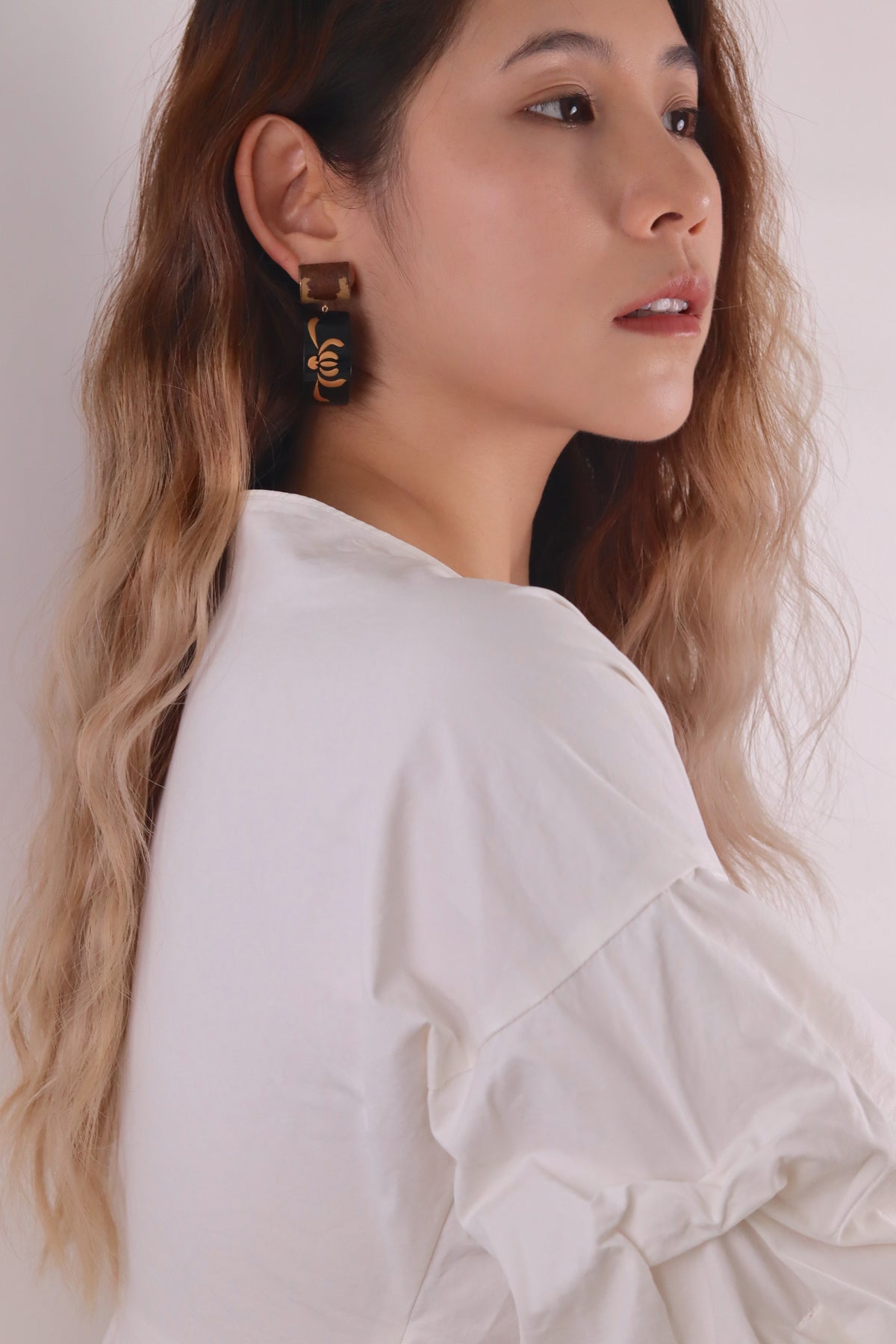 Tranquil Bamboo Lacquer Quasi-Maki-e Earrings — Woman wearing a white blouse with a plain background