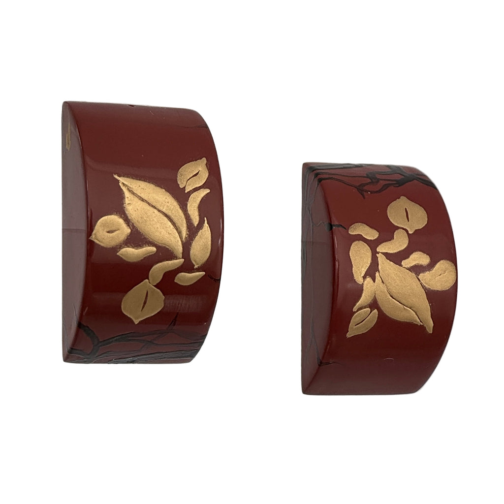 Tranquil Magnolia Lacquer Quasi-Maki-e Earrings — Two brown cylindrical objects with gold leaf designs on a white background