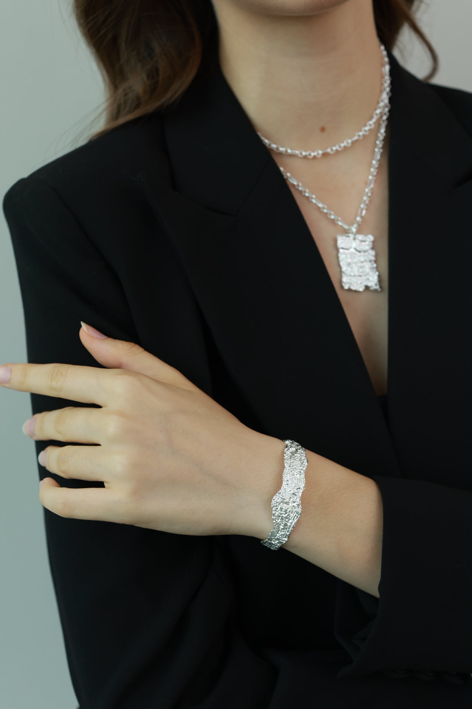 Person wearing a black outfit with jewelry including a bracelet and necklace.