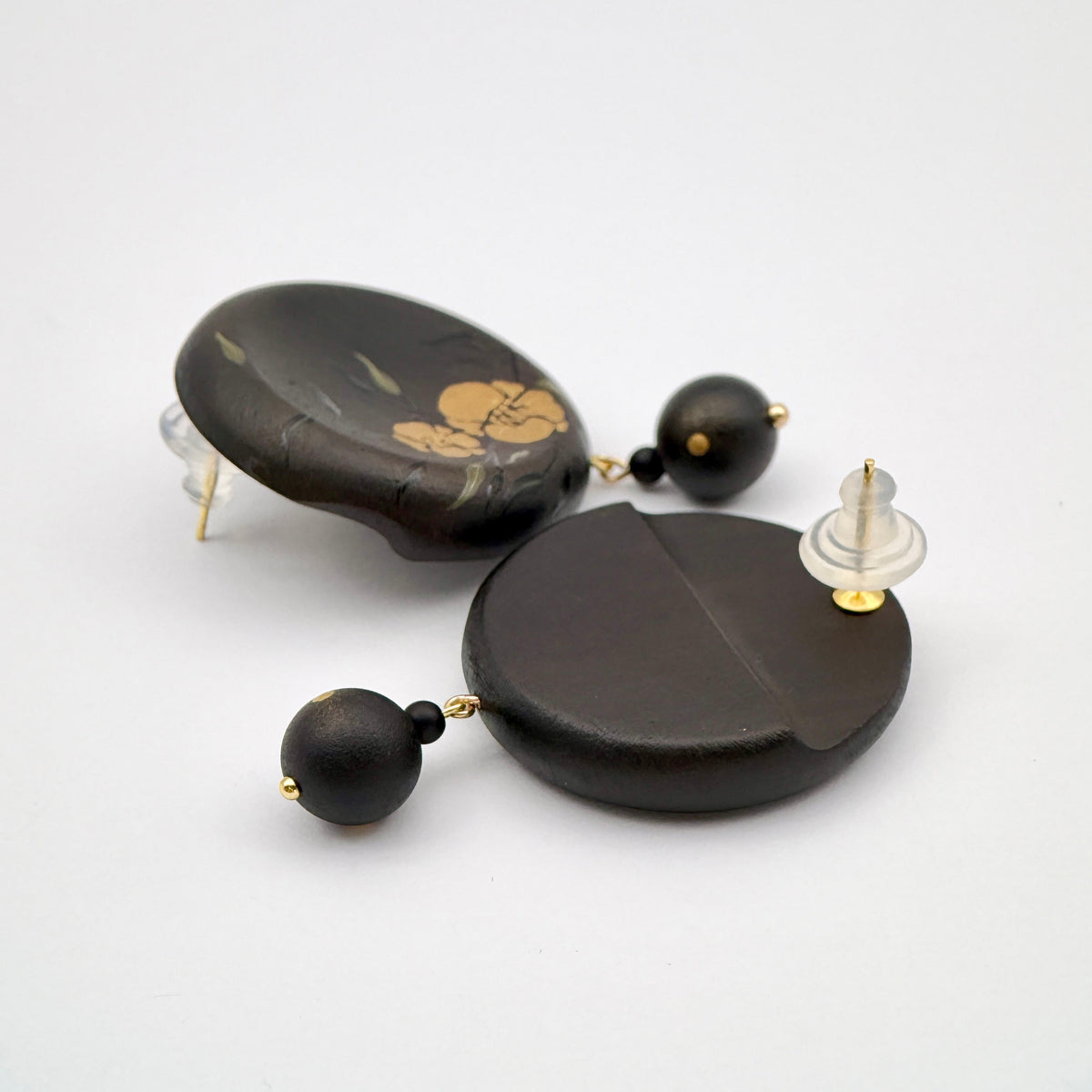 Twin Blossoms Black Lacquer Drop Earrings — Pair of black earrings with gold accents on a white background