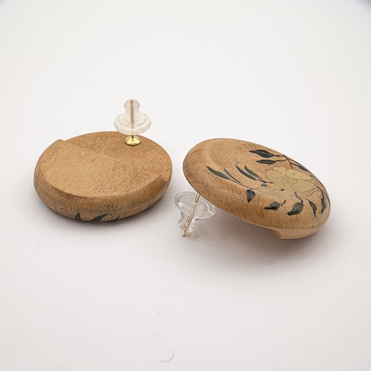 Twin Blossoms Natural Lacquer Earrings — Two cork-based products with decorative elements on a white background