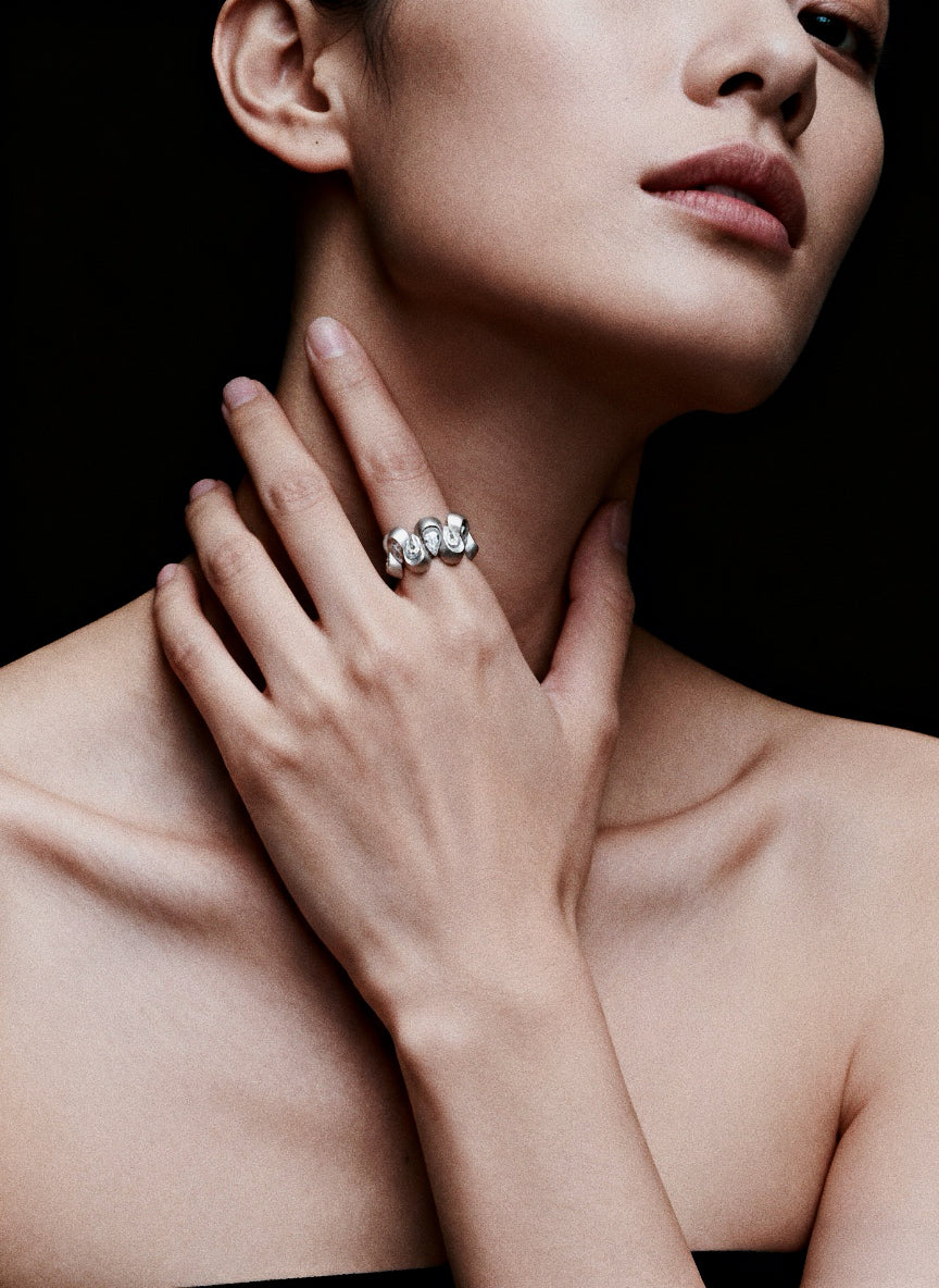 Undulating Form · Cubic Zirconia & Silver Ring — Close-up of a woman's hand wearing a diamond ring on a black background